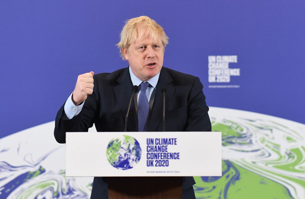 Britain's PM Boris Johnson behind a podium. The sign on the podium says UN Climate Change Conference UK 2020